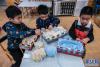 11月30日，孩子们在教室里用纸盒制作的工具编织爱心围巾。新华社记者 徐昱 摄