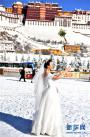 12月19日，一名女士在布达拉宫广场上拍婚纱照。 12月18日，西藏拉萨市迎来今年入冬以来的首场降雪。19日清晨，拉萨雪后初霁，处处银装素裹，尽显雪域高原之美。 新华社记者觉果摄