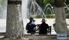 6月25日，两名市民在拉萨市一处喷泉旁乘凉。新华社发（孙非摄）