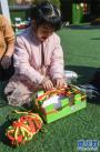12月11日，小朋友用纸盒制作的工具编织爱心围巾。 新华社记者 徐昱 摄