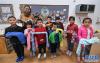 12月11日，小朋友们和老师一起展示编织好的爱心围巾。新华社记者 徐昱 摄