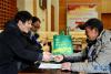 12月23日，在拉萨火车站，一名受助务工人员（右）从中国邮政集团公司西藏自治区分公司工作人员手中接过火车票。新华社记者 张汝锋 摄