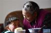 1月20日，在森布日极高海拔地区生态搬迁安置点，73岁的多吉卓玛在新居内给孙子喂饭。新华社记者 觉果 摄