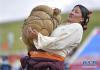 8月10日，一名妇女在参加抱石头比赛。新华社记者 张汝锋 摄