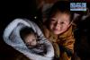 2月15日，在四川省红原县阿木乡卡口村，甲央贡嘎顿增在照看不足一个月大的妹妹。