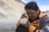 8月30日，在西藏日喀则市定日县，中科院地理科学与资源研究所客座教授李渝生使用放大镜观察岩石。
