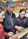 从新疆和田墨玉县来到西藏阿里狮泉河镇的阿卜杜杰力力·麦提如刚（中）给邻居们看自己的家庭合影（9月22日摄）。新华社发（索朗罗布 摄）
