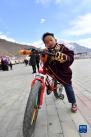 一位搬迁牧民家的孩子在荣玛高海拔生态搬迁点骑自行车玩耍（2月28日摄）。新华社记者 觉果 摄