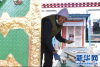 2月23日，曲水县三有村村民旺堆在自家门上刷漆。新华网 旦增努布 摄