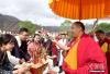 图为6月16日，西藏佛学院工作人员手捧象征吉祥如意的切玛欢迎班禅（右）。中新社发 李林 摄