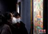 12月19日，西藏拉萨，观众正在欣赏展览中的唐卡。