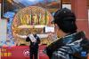 2月22日，在西藏博物馆，游客手持印有“吉祥八宝”图案的木刻印刷品拍照留念。新华社发（丁增尼达 摄）