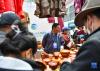 展会上的不丹商人向顾客销售不丹服装和木碗（6月18日摄）。新华社记者 晋美多吉 摄