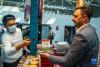 在第五届藏博会现场，来自印度的参展商伊纳亚特·艾哈迈德·汗（右）使用二维码收款（6月17日摄）。新华社记者 孙非 摄