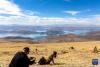游客在喀庆拉山上以羊卓雍错为背景拍照（4月5日摄）。新华社记者 姜帆 摄