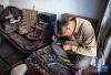  在扎西吉彩金银铜器厂，手工艺人在给银器錾刻花纹（3月9日摄）。新华社记者 孙非 摄
