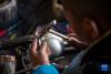 在扎西吉彩金银铜器厂，一名手工艺人在打制银器（3月9日摄）。新华社记者 孙非 摄